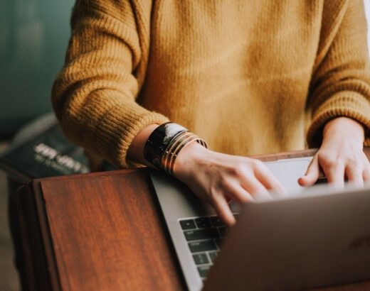 Persoon werkt op een laptop aan een houten tafel