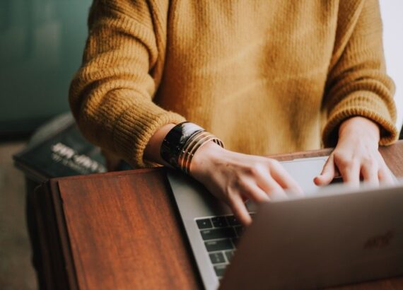 Persoon werkt op een laptop aan een houten tafel